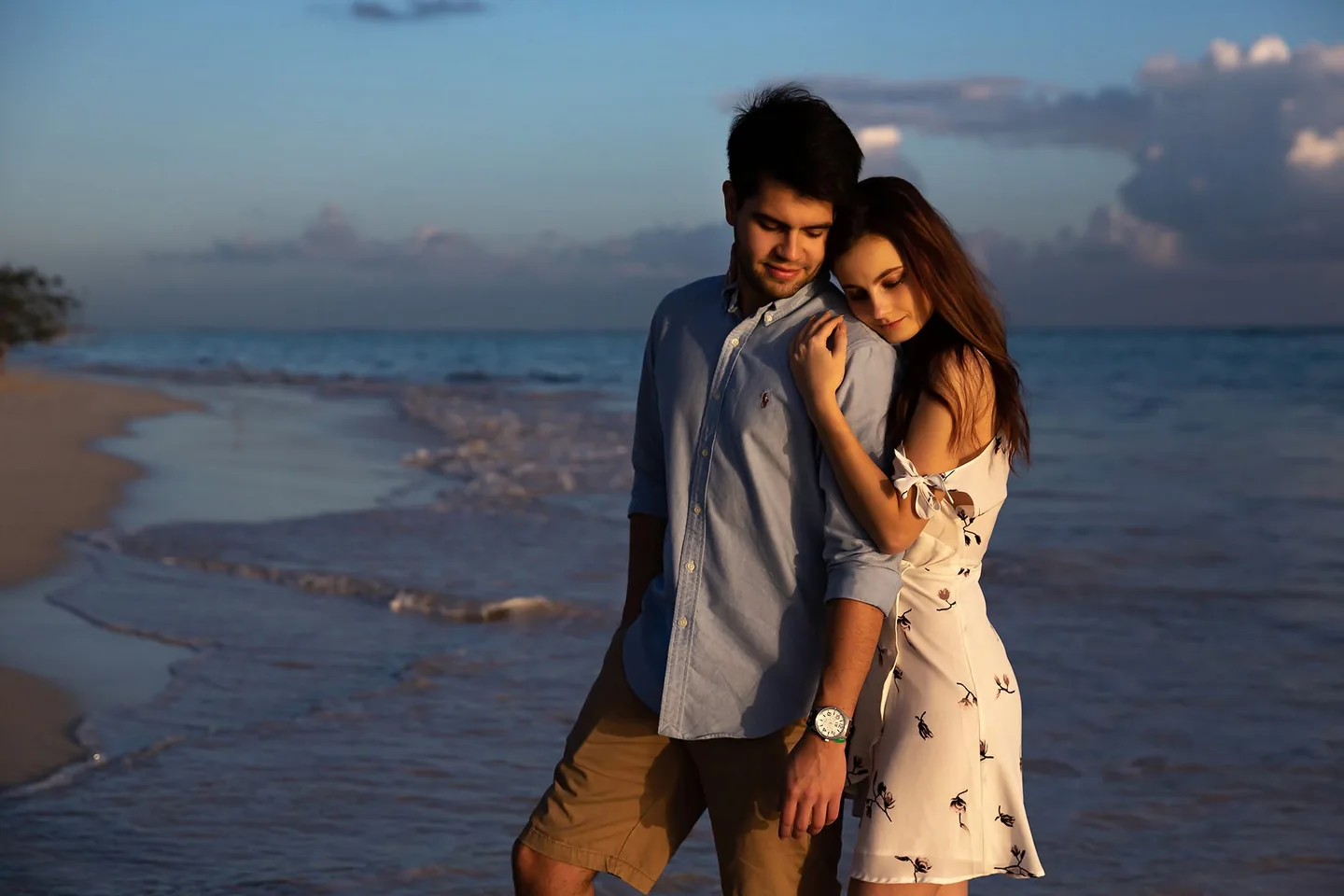 Woman resting her head on her partnerâ€™s shoulder during a beach portrait