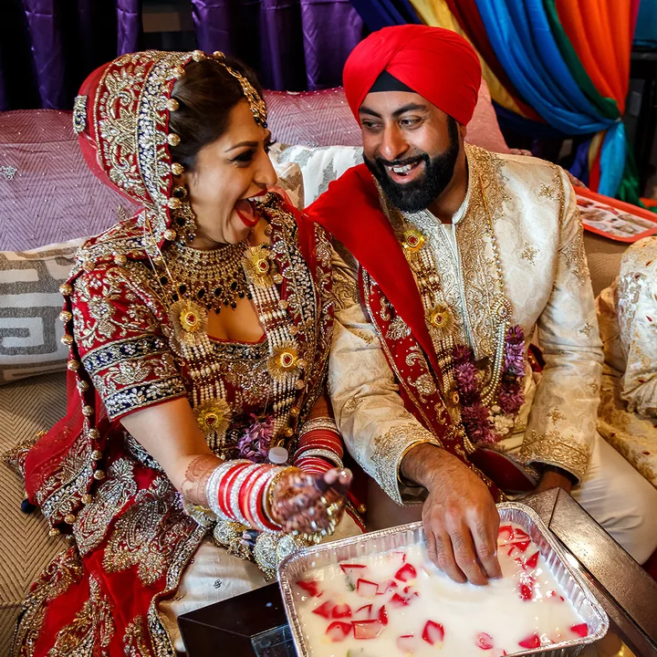 Wedding couple laughing as the groom reaches into a tray of water and petals