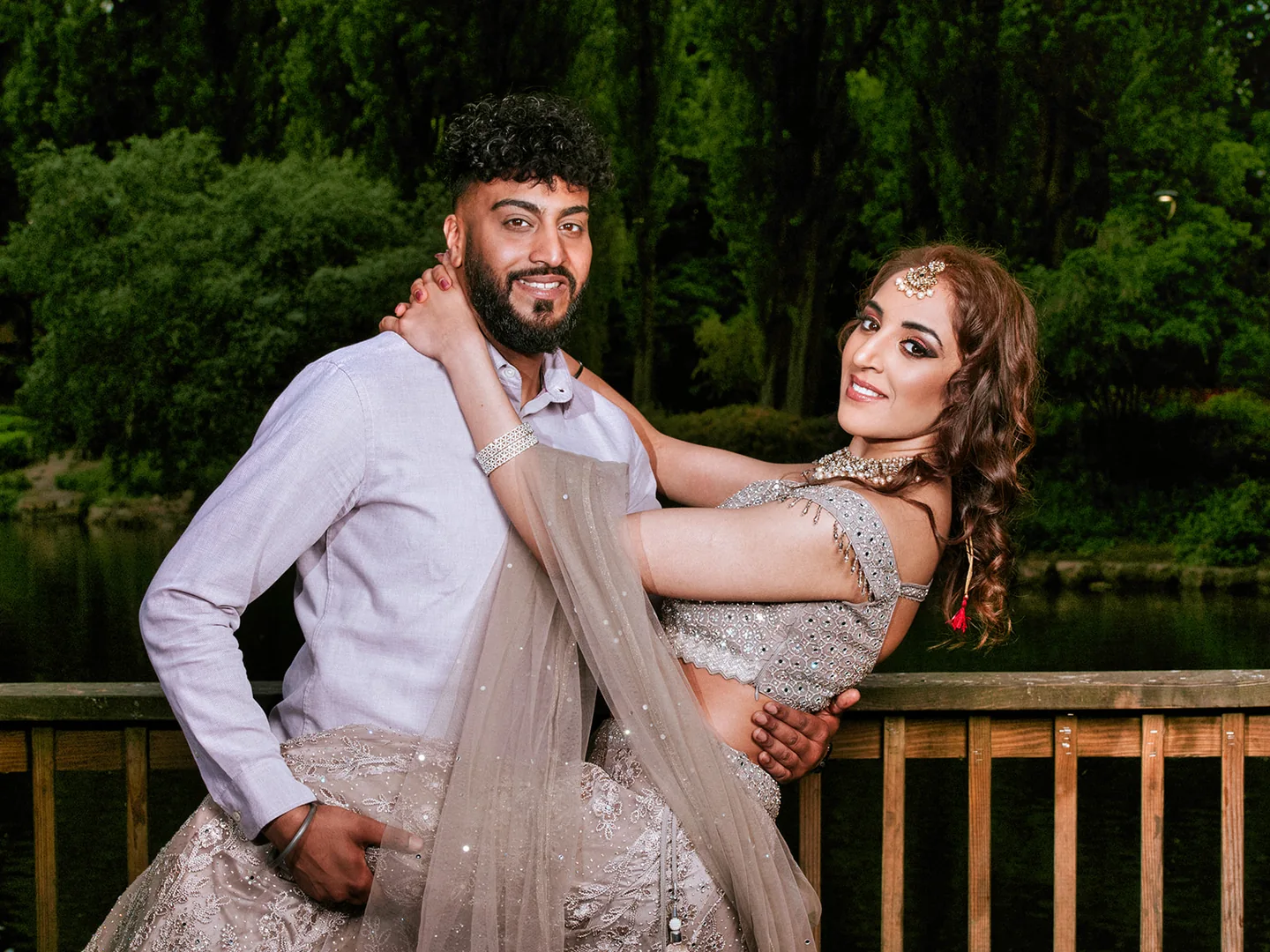 Couple posing together on a wooden terrace with trees behind them